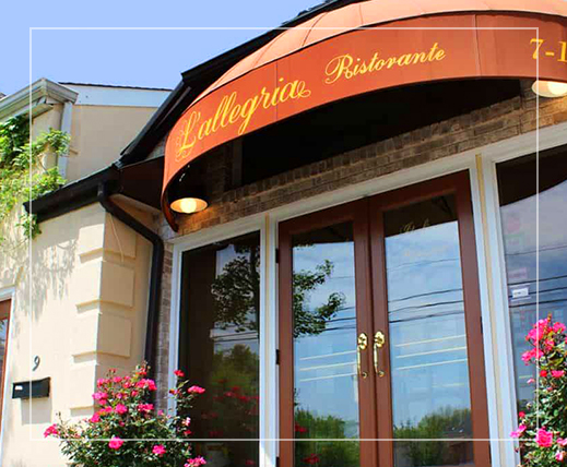 Entrance of L’allegria Restaurant with two pull-open doors underneath awning sign