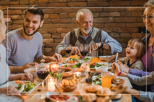 Family sitting around table and enjoying meal while laughing and talking in restaurant